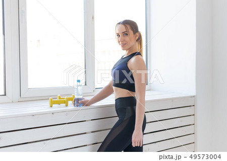 Workout, fitness and sport concept - pretty sporty woman standing near window in gym 49573004