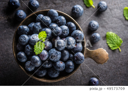 Vintage bowl full of fresh blueberries with herbs. Vintage bowl full of fresh blueberries with herbs. 49573709