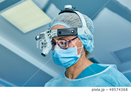 Close up portrait of female surgeon doctor wearing protective mask and hat during the operation Close up portrait of female surgeon doctor wearing protective mask and hat during the operation 49574368