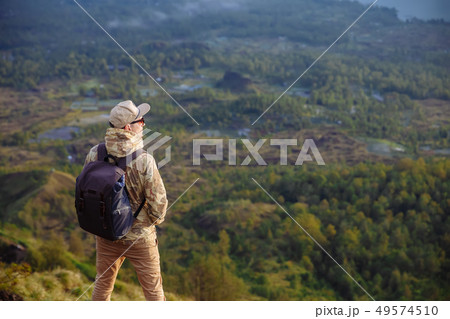 Man tourist looks at the sunrise on the volcano Batur on the island of Blai in Indonesia. Hiker man Man tourist looks at the sunrise on the volcano Batur on the island of Blai in Indonesia. Hiker man 49574510