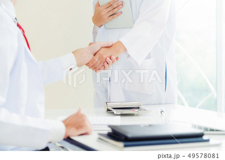 Doctor at hospital shakes hand with another doctor Doctor at hospital shakes hand with another doctor 49578081