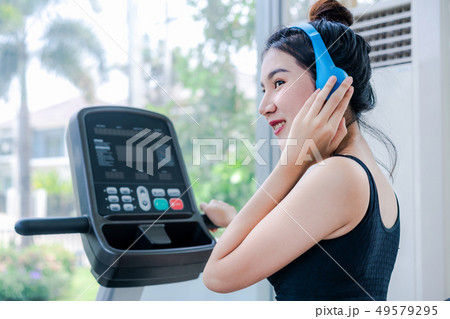 Woman runner listens to music and runs treadmill. Woman runner listens to music and runs treadmill. 49579295
