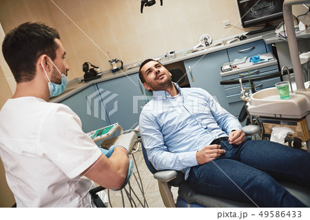 Make your dream smile a reality! Dentist in mask and latex gloves sitting near his patient in dental 49586433
