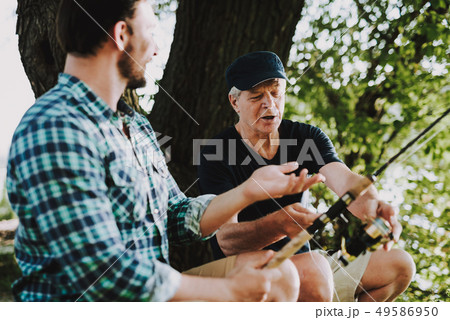 Old Father with Bearded Son Fishing on River. Old Father with Bearded Son Fishing on River. 49586950