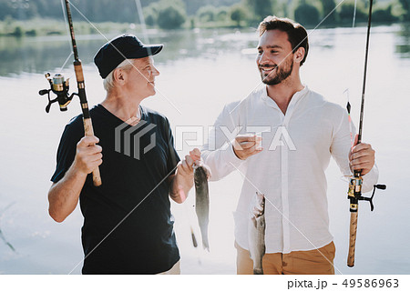 Old Father with Bearded Son Fishing on River. Old Father with Bearded Son Fishing on River. 49586963