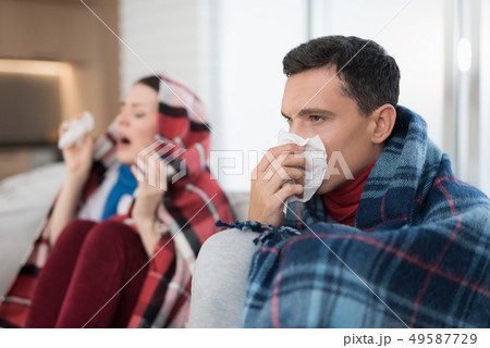 Sick Couple Sitting on Sofa in Checkered Blankets. 49587729