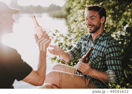 Smiling Men Drinking Beer near River in Summer. Smiling Men Drinking Beer near River in Summer. 49591622