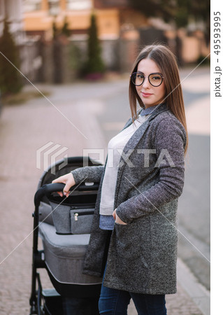 Family, child and parenthood concept - Happy mother with stroller in the park. Mom with sunglasses Family, child and parenthood concept - Happy mother with stroller in the park. Mom with sunglasses 49593995