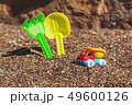 Children's toy truck with gravel or sand. Yellow scoop and green rake on the background. Concept of 49600126