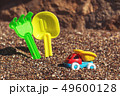 Children's toy truck with gravel or sand. Yellow scoop and green rake on the background. Concept of 49600128