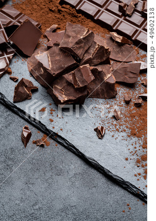Dark or milk organic chocolate pieces on dark concrete backgound Dark or milk organic chocolate pieces on dark concrete backgound 49602138