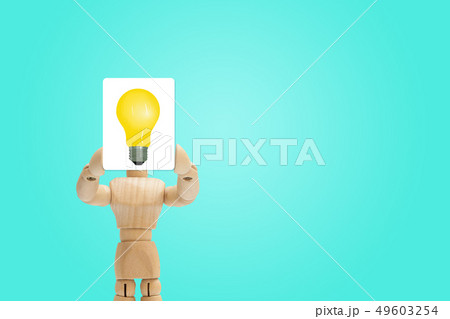 Wooden figure holding yellow light bulb. Wooden figure holding yellow light bulb. 49603254