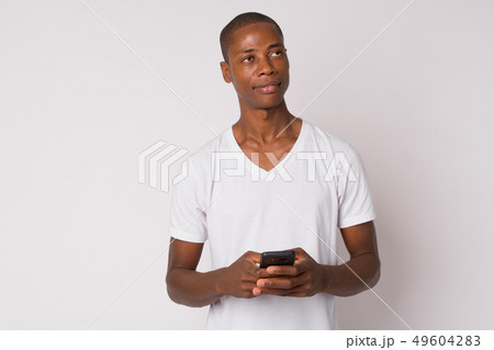 Portrait of young handsome bald African man thinking while using phone 49604283
