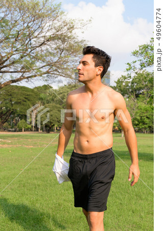 Profile view of young handsome shirtless Hispanic man at the park 49604774