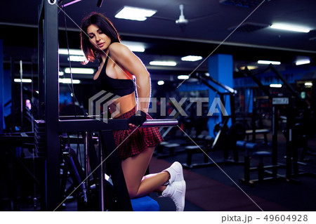 Young woman doing exercises for the back on fitness machine in gym, view from the back. Fitness Young woman doing exercises for the back on fitness machine in gym, view from the back. Fitness 49604928