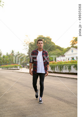 Young handsome Hispanic hipster man walking and thinking at the park Young handsome Hispanic hipster man walking and thinking at the park 49605068
