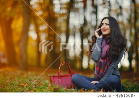 brunette girl using phone while at the park brunette girl using phone while at the park 49615687