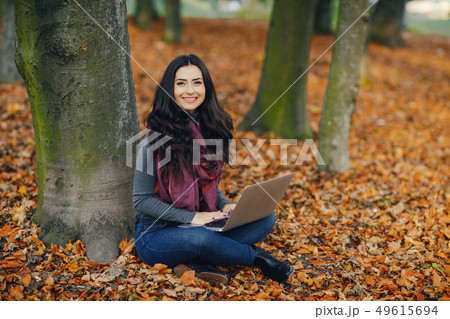 brunette girl working on her laptop in the park 49615694