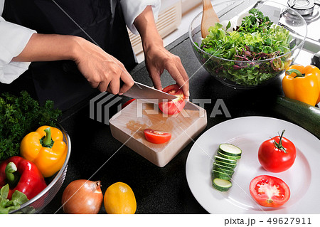 woman vegan cooking healthy food and preparing salad for dinner woman vegan cooking healthy food and preparing salad for dinner 49627911