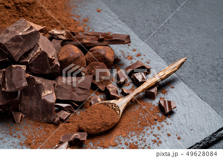 Dark or milk organic chocolate pieces and cocoa powder on dark concrete backgound Dark or milk organic chocolate pieces and cocoa powder on dark concrete backgound 49628084