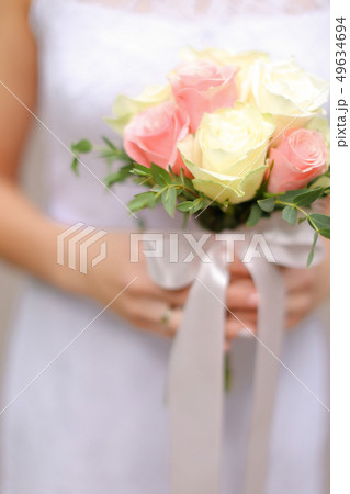 Close up cute bouquet of white and pink roses in bride hands. Close up cute bouquet of white and pink roses in bride hands. 49634694