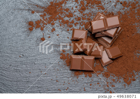 Dark or milk organic chocolate pieces and cocoa powder on dark concrete backgound Dark or milk organic chocolate pieces and cocoa powder on dark concrete backgound 49638071