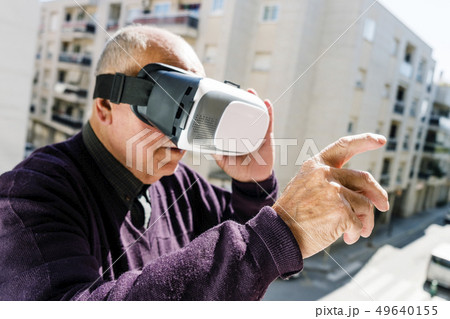 old caucasian man using a virtual reality headset. old caucasian man using a virtual reality headset. 49640155