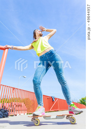 Teen girl skater riding skateboard on street. Teen girl skater riding skateboard on street. 49644957