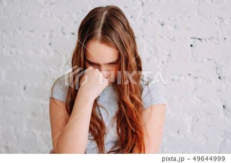 Sad teen girl with long curly red hair isolated  49644999
