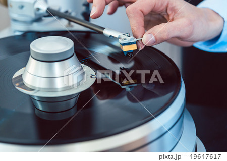 Woman putting needle on vinyl record on turntable 49647617