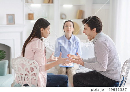 Couple arguing during therapy session with psychologist 49651387