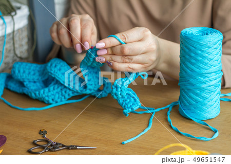 Hands of a young woman knit crochet from blue yarn Hands of a young woman knit crochet from blue yarn 49651547