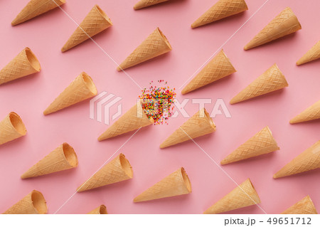 Waffle cones and sprinkles on pink surface 49651712
