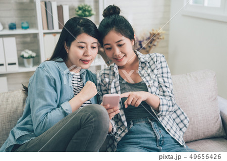 girls sharing earphones pointing show cellphone 49656426