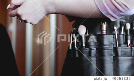 Professional make-up artist with a belt bag with tassels. makeup brushes Professional make-up artist with a belt bag with tassels. makeup brushes 49665839