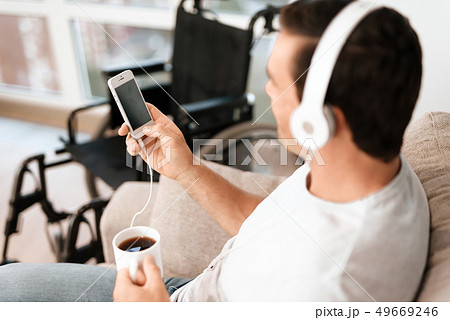 Man Listens to Music in Headphones and Drinks Tea Man Listens to Music in Headphones and Drinks Tea 49669246