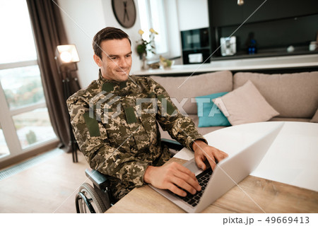 Military Man in Wheelchair Work on Laptop Indoors 49669413