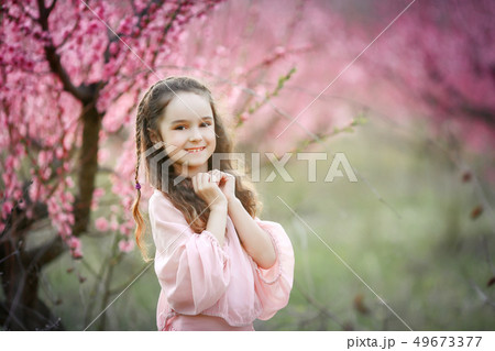 Beautiful young woman in pinkstylish garden dress blooming sakura 49673377