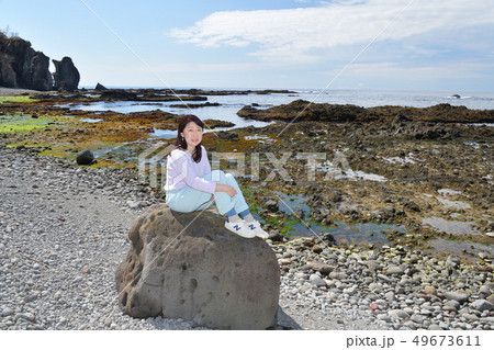 北海道せたな町長磯海岸で岩に腰掛ける黒髪の女性のポートレートを撮影 49673611
