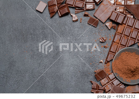 Frame or border made of Dark or milk organic chocolate pieces and cocoa powder on dark concrete Frame or border made of Dark or milk organic chocolate pieces and cocoa powder on dark concrete 49675232