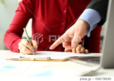Female employee holding silver pen making notes in documents 49679690