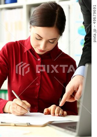 Female worker making notes in documents where male boss arm showing 49679691