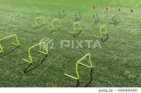 Yellow mini hurdles and orange cones on turf field 49680400