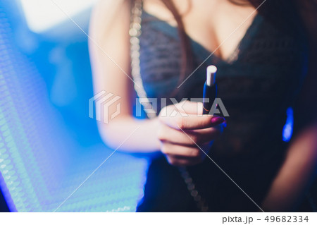 Electronic cigarettes, technology cigarette. Tobacco system IQOS. Female hand on blurred background Electronic cigarettes, technology cigarette. Tobacco system IQOS. Female hand on blurred background 49682334