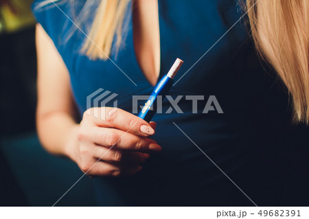 Electronic cigarettes, technology cigarette. Tobacco system IQOS. Female hand on blurred background Electronic cigarettes, technology cigarette. Tobacco system IQOS. Female hand on blurred background 49682391