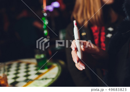 Electronic cigarettes, technology cigarette. Tobacco system IQOS. female hand on blurred background Electronic cigarettes, technology cigarette. Tobacco system IQOS. female hand on blurred background 49683823
