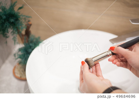 Makr up brush. Woman washing dirty makeup brush with soap and foam in the sink Makr up brush. Woman washing dirty makeup brush with soap and foam in the sink 49684696
