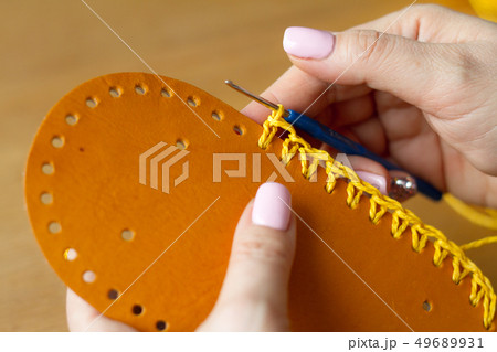 Hands of a young woman knit crochet from yellow 49689931