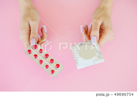 Pills or Condom. Antibiotics from venereal diseases. Concept of safe sex. Pills and condom lie on a Pills or Condom. Antibiotics from venereal diseases. Concept of safe sex. Pills and condom lie on a 49690754