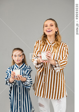 Cheerful long-haired sisters standing on grey background Cheerful long-haired sisters standing on grey background 49693030